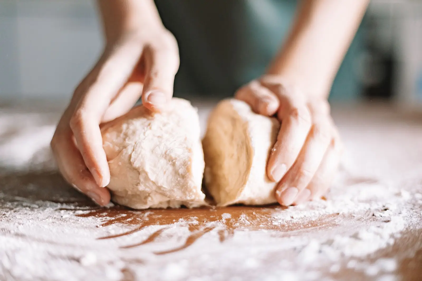 Hands shaping raw dough on a floured table